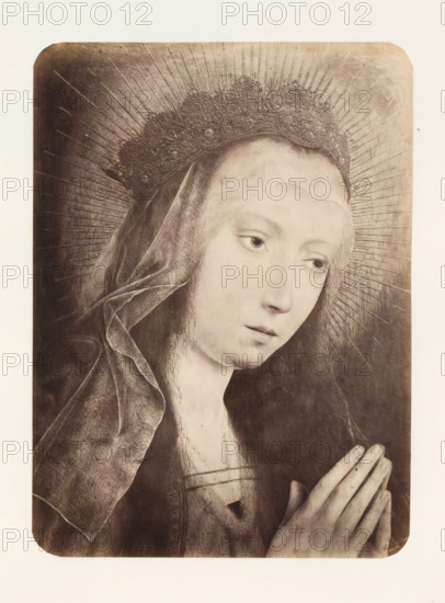 Photo reproduction of Mary in prayer by Quinten Massijs, photograph, reproduction, page, photographer: Edmond Fierlants, after painting by Quinten Massijs (I), publisher: C. Muquardt, Brussels, c. 1856 - in or before c. 1861, paper, albumen print, albumendruk, height 371 mm x width 272 mm, Mary praying, A sepia-toned portrait of a young woman shown from the shoulders up with a slightly bowed head and hands held together in a praying position, wearing a dark veil and an ornate crown with radiating lines behind it, her face is pale with downcast eyes and a calm expression, delicate fingers with visible knuckles are clasped together, the veil shows soft folds and texture, the crown has detailed embellishments and the background is plain with faint radial lines extending outward.