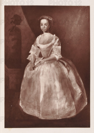 Photo reproduction of a painting depicting a portrait of Grace Naylor, reproduction, page, photomechanical print, cliché maker: Woodbury Permanent Photographic Printing Company, after painting by anonymous, c. 1866 - in or before 1876, photographer, paper, Woodburytype, height 132 mm x width 92 mm, Person, Grace Naylor, adolescent, young woman, maiden, historical persons (portraits and scenes from the life), A sepia-toned portrait of a woman standing and facing forward, wearing a wide, full skirt dress with a low neckline and short, ruffled sleeves; her hands are clasped at waist level, one hand holding a folded fan, and she has a calm, neutral facial expression with hair pulled back and a headband or small cap. The background is dark and plain with a lighter triangular area behind her and a darker vertical rectangular panel to her left that contains a shadowy silhouette resembling a carved or painted figure. The image has a narrow light border around the portrait and a slightly textur...