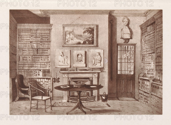 Photographic reproduction of a painting, depicting the interior of a library in the rectory of Herstmonceux, reproduction, page, photomechanical print, cliché maker: Woodbury Permanent Photographic Printing Company, after painting by Augustus Hare, Herstmonceux, c. 1866 - in or before 1876, photographer, East Sussex, paper, Woodburytype, Woodburytypie, height 84 mm x width 121 mm, study, 'studiolo', library, interior, representation of a building, A sepia-toned interior view of a room with tall bookshelves lining both sides, filled with rows of books; a round table with objects on it stands in front of a fireplace that has framed reliefs and a portrait above the mantel; a sculpted bust sits on a high shelf near a door with a window of panes; two chairs are placed near the table, one with a curved back and the other plain; a small rug lies beneath the table and a container rests on the floor beside the fireplace.