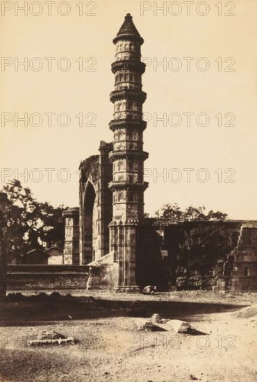 Mosque of Mahomed Ghous.- From the North, View of a minaret of the Mohammed Ghous Mosque in Ahmedabad, photograph, page, inscription: '2D2', number: '102.', photographer: Thomas Biggs, Ahmedabad (city), c. 1856 - in or before 1866, Gujarat, paper, albumen print, height 189 mm x width 137 mm, temple, shrine, Islam, Mohammedanism, Mohammed Ghous Mosque, A tall stone tower with multiple circular balconies rising above a partially ruined arched structure, surrounded by remnants of masonry and low walls, with patches of vegetation and trees visible behind and to the left of the buildings, and a foreground of bare ground scattered with small stone fragments.