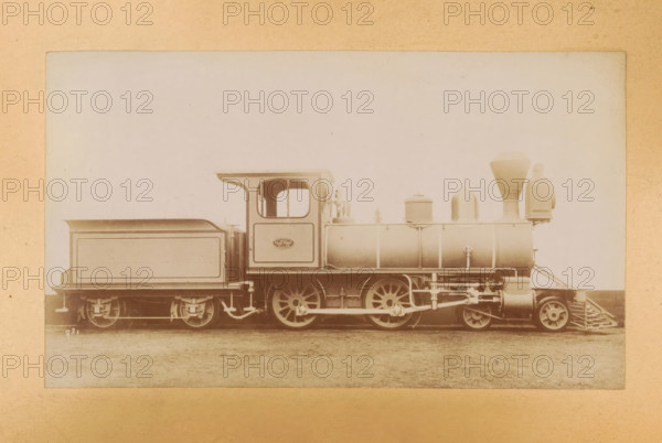Passenger steam locomotive made by Sharp, Stewart and Company, photograph, page, inscription: 'Class 981. Bogie passenger engine.', number: '981', c. 1874 - in or before 1884, photographer, paper, albumen print, height 83 mm x width 142 mm, steam locomotive, A sepia-toned photograph of a steam locomotive shown in profile, centered on a flat plain, with a rectangular tender behind the cab and a cylindrical boiler toward the front; the cab has an open window and a curved roof edge, the boiler features dome-shaped fittings and a tall funnel, and the front has a cowcatcher and a round headlamp assembly; visible are the large spoked driving wheels, connecting rods, and various mechanical linkages beneath the boiler, with the entire scene framed by a lighter matte border.