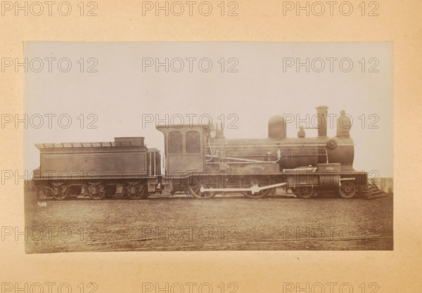 Passenger steam locomotive made by Sharp, Stewart and Company, photograph, page, inscription: 'Class 938. Bogie passenger engine. Compounded on Worsdell & Von Borries' System.', number: '938', c. 1874 - in or before 1884, photographer, paper, albumen print, height 82 mm x width 143 mm, steam locomotive, A sepia-toned photograph of a steam locomotive and its tender shown in profile, centered on a light background with a darker ground beneath, featuring a large cylindrical boiler with piping and fittings along its side, a rounded dome near the middle, a vertical chimney toward the front, and a cab with louvered panels and a curved roof; the tender has a rectangular tank with molded panels and a railing on top, both vehicles have large spoked driving wheels, visible connecting rods and suspension components, and a cowcatcher at the front, with the image framed by a plain border of aged paper.