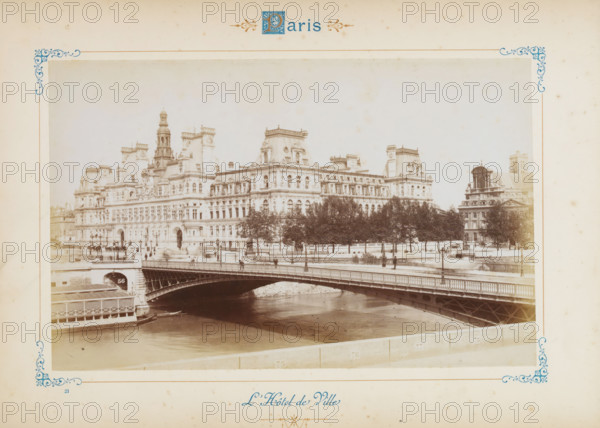 The City Hall, View of the Paris City Hall, photograph, page, number: '56', Paris, c. 1879 - c. 1889, photographer, paper, albumen print, height 120 mm x width 188 mm, town hall, façade (of house or building), City Hall (Paris), A sepia-toned photograph framed by a decorative border shows an ornate multi-story stone building with mansard roofs, dormer windows, sculpted facades, and a tall central tower, set behind a row of trees along a riverside embankment; in the foreground an arched metal bridge spans a calm river with a boat moored near the riverbank, lampposts line the bridge and embankment, and a smaller domed building is visible to the right of the main structure.