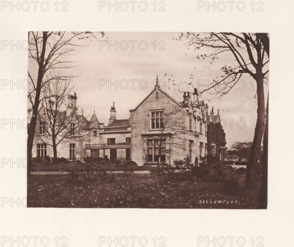 Gallowflat, photograph, page, photographer: Thomas Annan, Rutherglen, c. 1868 - in or before 1878, paper, carbon print, height 115 mm x width 160 mm, rural housing, eg country-house, villa, cottage, façade (of house or building), A sepia-toned photograph of a large stone house with steep gables and multiple chimneys, framed by tall leafless trees whose branches extend across the sky, a foreground of dark grass and low shrubs, and windows and architectural details visible on the building's facade.
