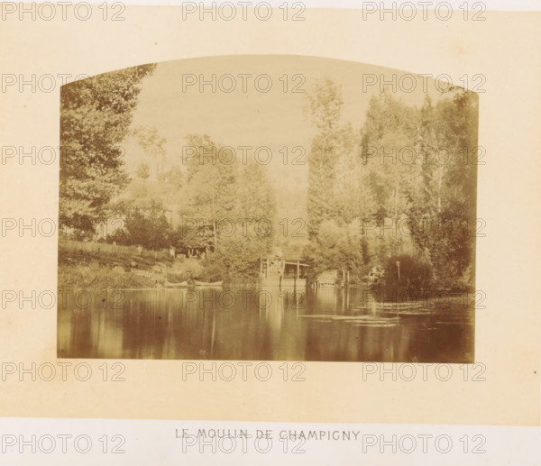 Le moulin de Champigny, Marne in Champigny-sur-Marne, photograph, page, photographer: Ildefonse Rousset, Champigny-sur-Marne, c. 1860 - in or before 1865, paper, albumen print, height 115 mm x width 156 mm, river, Marne (river), A faded sepia photograph shows a riverside scene framed by tall trees on both sides, their foliage dense and varied in texture. Along the near bank there is a wooden fence and a small building partially obscured by trees. A wooden structure extends over the water, with a dock area and what appear to be small boats moored nearby. The water surface is calm and reflective, mirroring the trees and structures with soft, vertical ripples and patches of lighter texture. The overall image has an arched top and a broad pale border surrounding it.