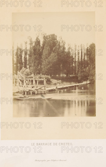 Le barrage de Creteil, Dam in the Marne in Creteil, photograph, page, photographer: Ildefonse Rousset, Créteil, c. 1860 - in or before 1865, paper, albumen print, height 151 mm x width 120 mm, river, dam (in canal), Marne (river), A sepia-toned photograph showing a calm river with a wooden pier and a simple wooden structure extending over the water, a small rowboat moored near the foreground, a narrow plank bridge crossing to the opposite bank, a few people sitting or standing on the pier and bridge, and a dense line of tall trees filling the background with reflected shapes on the river surface.