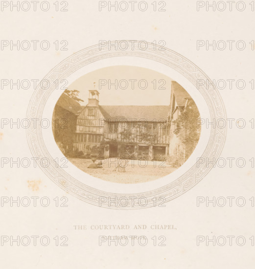Courtyard and chapel of Ightham Mote near Ightham, The courtyard and chapel, Ightham Mote, photograph, page, photographer: Stephen Thompson, Ightham, c. 1866 - in or before 1876, Kent, paper, albumen print, albumendruk, height 70 mm x width 89 mm, courtyard, rural housing, eg country-house, villa, cottage, church (exterior) - QQ - small church, chapel, A sepia-toned circular photograph framed by an ornate patterned border shows a timber-framed building with a pitched roof and a small bell tower above one gable; the facade features exposed beams, mullioned windows, and an open arcade at ground level partially covered in climbing plants, with a gravel courtyard in front containing a decorative stone urn on a pedestal and a folded metal chair, flanked by trees and foliage on either side.