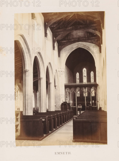 Emneth, photograph, page, photographer: Edward Johnson, Saint Edmund's Church (Emneth), c. 1858 - in or before 1869, Edward Johnson, photographer, Norfolk (county), paper, albumen print, height 178 mm x width 123 mm, interior of church, parts of church interior: aisle, The photograph shows the interior of a church with a central aisle flanked by rows of wooden pews and tall stone arches along one side, slender columns supporting rounded archways, a carved wooden screen separating the nave from the chancel, three tall arched stained glass windows visible above the screen, dark wooden roof beams with visible trusses above the chancel, and a pulpit and lectern near the front.