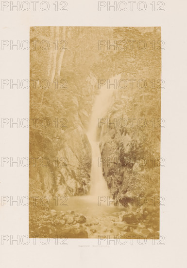 Barrow Waterfall, View of a waterfall in the Lake District, photograph, page, photographer: RJ Sproat, Lake District, c. 1857 - in or before 1870, paper, albumen print, height 166 mm x width 103 mm, waterfall, A tall, narrow sepia-toned photograph of a waterfall framed by steep rocky cliffs and dense foliage, showing water cascading down a narrow chute into a calm pool surrounded by scattered rocks, with trees and undergrowth visible along the cliff edges and rocky surfaces textured with moss and crevices.
