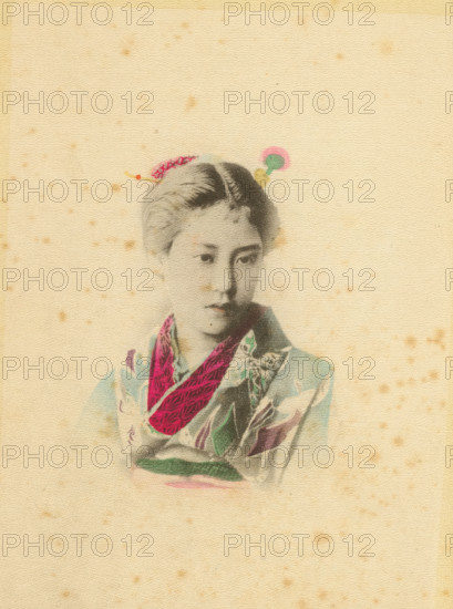 A damsel, page, photomechanical print, Japan, cliché maker: Kazumasa Ogawa, c. 1886 - in or before 1896, photographer, paper, crepe paper, collotype, hand coloring, height 176 mm x width 124 mm, adult woman, A faded portrait of a young person wearing a patterned garment with a bright scarf draped around the neck, the face rendered in soft grayscale with a neutral expression and short hair, small decorative hair ornaments visible atop the head, all set against a textured, aged beige background with scattered small brown speckles.