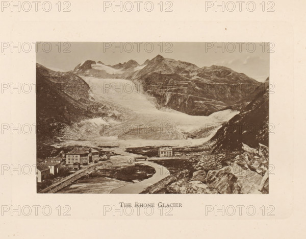 The Rhone Glacier, View of the Rhône Glacier in Switzerland, page, photomechanical print, Switzerland, c. 1874 - in or before 1884, paper, collotype, photoprint, height 86 mm x width 132 mm, glacier, Rhône glacier, A sepia-toned landscape photograph shows a wide glacial valley flanked by steep rocky mountains with snow and ice on their upper slopes, a broad ice flow descending toward the foreground, a winding river or meltwater stream running through the valley, scattered rocks and boulders on the slopes, and several multi-story buildings near the riverbank with pitched roofs and rectangular windows.