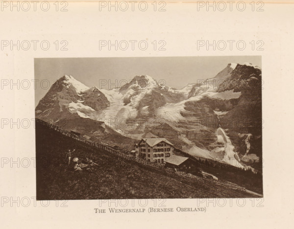 View of the Wengernalp in the Bernese Oberland, The Wengernalp (Bernese Oberland), page, photomechanical print, Bern (canton), c. 1874 - in or before 1884, paper, collotype, photoprint, height 86 mm x width 136 mm, mountains, mountain-range, snow peaks, A sepia-toned photograph shows a steep grassy hillside with a wooden fence running diagonally across it, a multi-story chalet-style building with a pitched roof and multiple windows situated partway down the slope, and a rugged mountain landscape behind with jagged peaks capped in snow and glaciers flowing down rocky faces, while a steep waterfall or icefall descends on one side of the mountains.