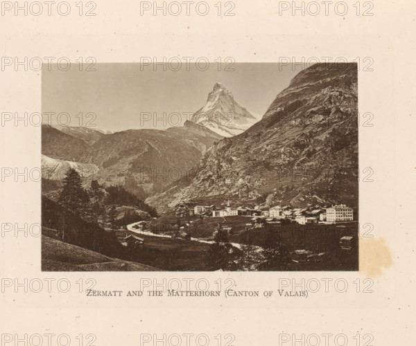 View of Zermatt and the Matterhorn, Zermatt and the Matterhorn (Canton of Valais), page, photomechanical print, Valais (canton), c. 1874 - in or before 1884, paper, collotype, photoprint, height 85 mm x width 130 mm, mountains, Zermatt, Matterhorn, A sepia-toned landscape photograph framed by a wide pale border shows a mountain peak with a jagged, snow-covered summit rising above steep rocky slopes; below the peak a valley contains clustered buildings including a church with a steeple and several multi-story structures, a winding river or stream flowing through fields and past small trees, and wooded hillsides and rocky outcrops on either side.