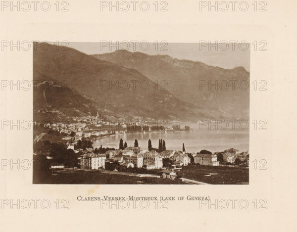 View of Clarens, Vernex and Montreux on Lake Geneva, Clarens-Vernex-Montreux (lake of Geneva), page, photomechanical print, Montreux, c. 1874 - in or before 1884, paper, collotype, photoprint, height 86 mm x width 130 mm, lake, prospect of city, town panorama, silhouette of city, A sepia-toned photograph showing a lakeside town at the foot of large, sloping mountains with a calm body of water along the town's edge; rows of multi-story buildings with pitched roofs occupy the foreground and extend toward the shoreline, where a line of tall, narrow trees stands near the water; beyond the trees a curved bay and waterfront structures are visible, with the mountains rising behind the town in layered ridges and rocky contours; the image is framed by a wide pale border with visible paper texture.