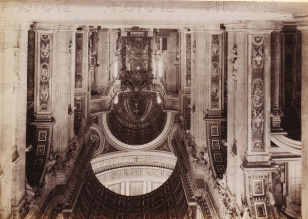 Interior of St. Peter's Basilica in Vatican City, photograph, page, Vatican City, c. 1850 - in or before 1860, photographer, paper, albumen print, height 97 mm x width 135 mm, interior of church, St. Peter's Basilica, An inverted sepia photograph showing an ornate interior with tall fluted columns and decorative pilasters, each panel embellished with carved figures and circular medallions; a large coffered dome with concentric decorative rings and sculptural details dominates the central area, framed by archways and richly patterned cornices; elaborate reliefs and statues sit atop ledges and niches, and decorative mouldings and geometric panels cover the walls and arches, all rendered in varying tones of brown and beige.