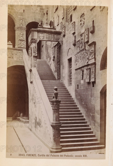 Firenze. Cortile del Palazzo del Podestà: secolo 1878 - in or before 1888, Edizioni Brogi, photographer, Florence, Tuscany, Palazzo del Podestà (Florence), paper, albumen print, height 145 mm x width 94 mm, façade (of house or building), inner court of palace or 'hôtel', A stone staircase ascends beside a tall masonry wall adorned with rectangular relief panels and sculpted plaques; the staircase has a smooth balustrade and is flanked at its lower end by a carved column topped with a lion figure. At the top of the stairs a decorated archway with reliefs and sculpted elements spans the width and rests on ornate pilasters, while arched openings and a dark recessed archway appear to the left. The stone surfaces show varied textures and weathering, with patterned carvings and ornamental details visible on columns, panels, and the architrave above the stairs.