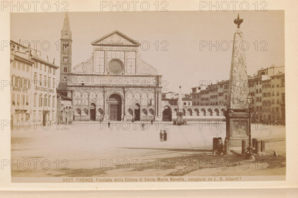 Firenze. Facciata della Chiesa di Santa Maria Novella, compluta da LB Alberti ?, Facade of the Santa Maria Novella in Florence, photograph, page, photographer: Edizioni Brogi (possibly), Florence, c. 1878 - in or before 1888, Tuscany, paper, albumen print, height 93 mm x width 148 mm, church (exterior), facade (of house or building), Santa Maria Novella, A wide sepia photograph of a large stone church facade with a tall square bell tower to one side and a round window feature above the central entrance; the church front has decorative arches and pilasters and three doorways with the central door larger and framed by an arch. In front of the church is an open paved square with a few small indistinct figures scattered across it and a pair of children standing close together near the center. To the right foreground stands a tall obelisk-like stone monument on a square base with a decorative top, beside a vintage street lamp and low bollards; behind it a row of arched colonnades and multi-...