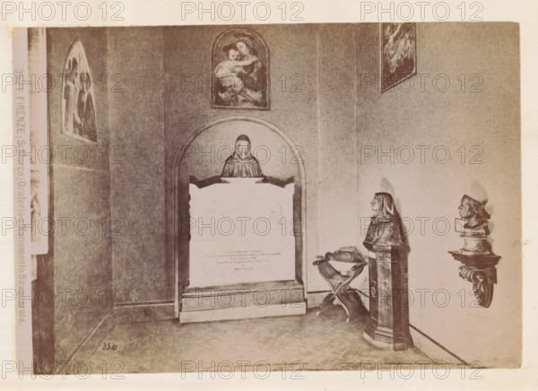 Oratory in the San Marco Monastery in Florence with a monument to Girolamo Savonarola, Firenze (S. Marco) Oratorio e Monumento Savonarola, photograph, page, number: '3521.', photographer: Fratelli Alinari (possibly), San Marco, c. 1878 - in or before 1888, Florence, Tuscany, paper, albumen print, height 100 mm x width 144 mm, monument, statue, abbey, monastery, convent, Roman Catholic church, interior, representation of a building, A sepia-toned interior scene showing a wall with framed religious paintings and sculpted busts mounted on pedestals, a recessed arched niche containing a plaque topped by a carved figure, an ornate basin with crossed supports standing beside a tall pedestal, and a tiled floor leading to the corner of the room.