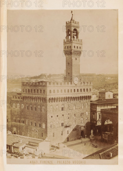 Exterior of the Palazzo Vecchio in Florence, Firenze - Palazzo Vecchio, photograph, page, number: '4043.', Florence, c. 1880 - in or before 1890, photographer, Tuscany, paper, albumen print, height 138 mm x width 100 mm, façade (or house or building), hôtel, ie small palace in city, Palazzo Vecchio, A tall stone tower with a crenellated top rises from a large rectangular stone building with rows of arched windows and decorative arches along its upper facade, a round clock face mounted on the tower above the building, a statue on a pedestal near the building's entrance, a street area with a few indistinct figures and a horse-drawn carriage, tiled rooftops in the foreground, and a hazy landscape of low hills and scattered buildings in the background.