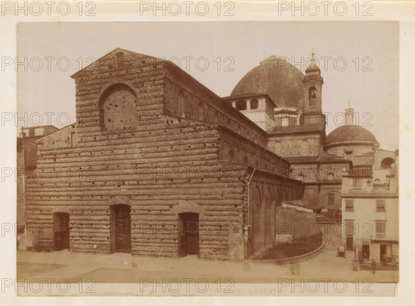 Firenze. Chiesa di S. Lorenzo, Exterior of the Basilica of St. Laurence in Florence, photograph, page, number: '4016', Florence, c. 1880 - in or before 1890, photographer, Tuscany, paper, albumen print, height 100 mm x width 137 mm, church (exterior), facade (of house or building), St. Lawrence Basilica, A sepia-toned photograph of a large stone building with horizontal banding and a triangular gable, showing arched and rectangular openings and wooden doors at ground level, with a long side façade featuring a row of small arched windows and an upper level with larger openings; behind and to the right there are domed roofs, one large dome with a smaller dome and a bell tower topped by a decorative finial, and adjacent multi-story buildings with balconies and shuttered windows; the foreground shows a paved area and a curved railing leading toward the rear, with faint human figures and a horse-drawn cart near the right edge.