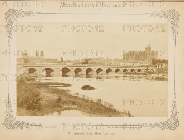 View of Metz and a bridge over the Moselle river, View of Moselfort from Metz and its surroundings, photograph, page, number: '3.', photographer: C. Holt, Metz, publisher: Verlag der Deutschen Buchhandlung, c. 1865 - in or before 1875, paper, albumen print, albumendruk, height 96 mm x width 155 mm, city-view, and landscape with man-made constructions, bridge in city across river, canal, A sepia-toned panoramic photograph shows a stone arched bridge spanning a calm river, with multiple semicircular arches reflected in the water below. Beyond the bridge a low riverside town stretches along the far bank, featuring rows of buildings with pitched roofs and a large Gothic cathedral with visible buttresses and a tall central tower dominating the skyline on the right. On the left a pair of square church towers and other steeples rise above the rooftops. In the foreground riverbanks with grasses and marshy vegetation lead to the water, and a small vegetated islet sits near the center of the riv...