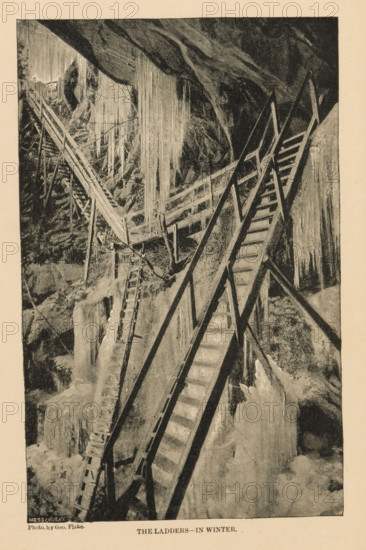The Ladders - in Winter, Ladders against a mountainside with icicles, page, photomechanical print, photographer: George Fiske, Yosemite Valley, cliché maker: Moss Engraving Co., New York (city), c. 1881 - in or before 1886, North America, California, paper, printing block, height 164 mm x width 102 mm, ice, freezing weather, ladder, A vertical monochrome illustration showing a steep rocky interior with long icicles hanging from the ceiling and walls, wooden ladders and stair-like structures angled across the scene with handrails and support beams, rough textured rock surfaces and frozen formations around the ladders, a narrow wooden walkway crossing between rock faces, and varied shading suggesting depth and shadow throughout the composition.