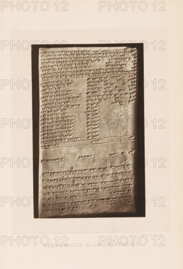 Terra cotta bilingual tablet, Clay tablet with bilingual inscription, page, photomechanical print, photographer: Stephen Thompson, c. 1871 - in or before 1876, paper, Woodburytype, height 121 mm x width 78 mm, excavation, archaeology, clay tablet, stone tablet, A vertical rectangular stone tablet with rows of incised wedge-shaped markings sits within a dark rectangular frame on a light background; the tablet surface shows horizontal lines separating sections and areas of denser and sparser markings, with some small chips and worn spots on the stone, and a narrow margin of the frame visible around the tablet.