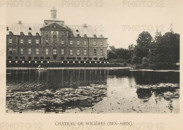 Chateau de Solières (Ben-Ahin), View of Château de Solières in Ben-Ahin, page, photomechanical print, photographer: attributed to Victor Gaillard, Huy, cliché maker: attributed to Emile Aubry, Brussels, c. 1885 - in or before 1890, Hoei, Attributed to, paper, collotype, photoprint, height 104 mm x width 155 mm, castle, A large multi-story stone building with a central pediment and a small dome on the roof sits along a waterfront, its rows of rectangular windows and arched openings reflected in the water below; a small rowboat with a figure is on the water near the building, and dense trees and shrubs occupy the right side of the scene, their foliage contrasting with the building's facade and also reflected in the rippling surface of the pond.