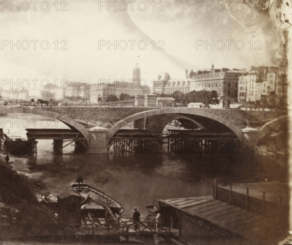 Construction of the Pont Louis-Philippe in Paris, stereograph, photographer: Charles Nègre, Paris, 1860 - 1862, paper, albumen print, albumen print from glass negative, height 82 mm x width 197 mm, river, bridge, Pont Louis-Philippe, A sepia-toned scene showing a stone arch bridge crossing a river with wooden scaffolding and pilings beneath some arches, small rowboats moored along the near bank, a person standing on a landing near the boats, another person in a small boat on the water, a cart with a horse and a driver on the bridge, distant multi-story buildings and trees along the far bank, and a cloudy sky above.