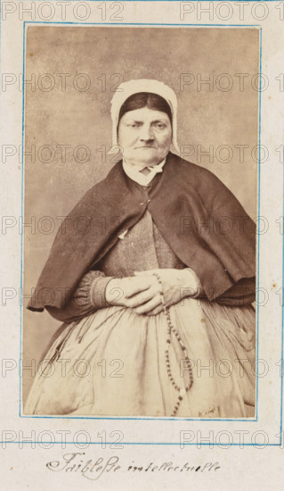 Portrait of a patient in a lunatic asylum, possibly Salpêtrière, photograph, : 'intellectual weakness', c. 1860 - c. 1885, photographer, paper, albumen print, height 92 mm x width 55 mm, historical persons not known by name - BB - woman, lunatic asylum, mental home, emotional illness, derangement, madness, A sepia-toned portrait of an older woman wearing a plain white cap and a dark shawl over a dress, seated with her hands folded in her lap holding a beaded rosary, framed by a thin blue-lined border on aged paper.