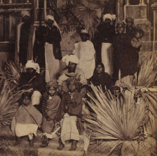 Group portrait with persons in India, Hindus, Faces and landscapes in Europe, Africa and Asia, Geographical Sculpture Gallery, collected by MJ Broekhuijsen, Head of a school in Amsterdam, stereograph, Numbered C9. bottom left of photo, annotation: 'Together with the Dravida tribes (see pl. 10), they form the principal component of the population of India. Both the Hindus and by far the majority of the Dravidas are gentle, patient, submissive people. Many distinguish themselves by an admirably beautiful physique, appearing just as beautifully in their distinctive attire as the fineness and regularity of their facial features beneath the richly pleated turban. Agriculture provides them with food (not in abundance), and the Hindu needs not much more than that. Among the Dravidas the desire for ostentation still prevails, and many a Tamil girl carries a fortune on her head, arms, and legs, carrying gold and silver with her.', annotation: 'Voor-Indië', India, publisher: Merkelbach & Co., Am...