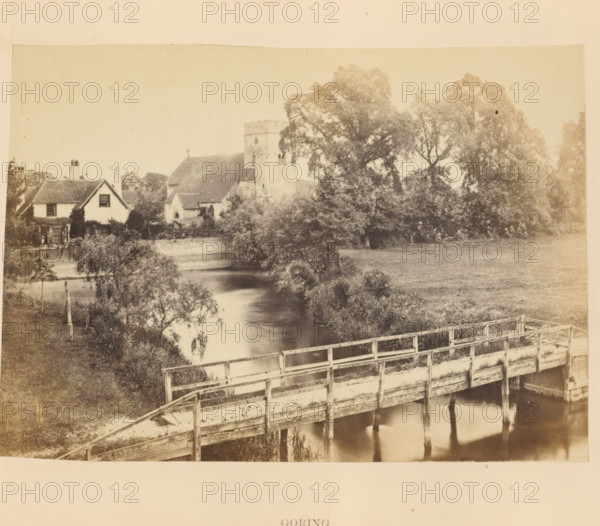View across the Thames at Goring-on-Thames, Goring, photograph, page, photographer: attributed to Francis Frith, Goring-on-Thames, c. 1862 - in or before 1867, Oxfordshire, Attributed to, paper, albumen print, height 100 mm x width 140 mm, river, Thames, A sepia-toned scene shows a wooden footbridge crossing a calm river, the bridge having railings and visible support posts reflected in the water below. On the far bank there are trees and bushes lining the river, with a grassy field extending back from the water. Behind the trees a church with a square tower and pitched roof is partially visible, and nearby there is a cottage with a pitched roof, chimneys, and windows, some climbing plants on its walls. The image has a soft, slightly faded appearance and an empty sky above the treeline.