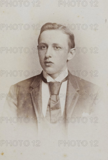 Portrait of a young man, album page, photograph, carte-de-visite, This photo is part of an album., photographer: Jan Goedeljee, Leiden, 1860 - 1905, paper, pasteboard, albumen print, albumendruk, height 83 mm x width 52 mm, historical persons, A faded sepia portrait of a young man from the chest up wearing a dark jacket over a light waistcoat and a wide cravat tied under a high white collar; his hair is neatly combed and he gazes slightly off center with a neutral expression, and the background is plain and lightly mottled.
