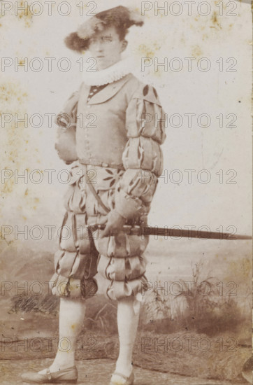 Portrait of a young man in costume with a sword, identified as WU van Lanschot, album page, photograph, carte-de-visite, This photo is part of an album., name: 'WU van Lanschot., 237.', inscription: 'H. Jonker, Apothekersdijk No. 7, Leiden., The printing plate is kept for further orders, Reproductions and Enlargements in all Genres.', photographer: Hendrik Jonker, Leiden, 1872 - 1900, paper, pasteboard, albumen print, height 83 mm x width 52 mm, historical persons, hacking and thrusting weapons: sword, historical costume, A faded sepia photograph of a person standing and facing forward wearing a historical costume with a wide ruffled collar and a hat with a large plume, a fitted doublet with decorative buttons and puffed sleeves, and voluminous slashed breeches gathered into padded segments; one hand rests on the hip while the other holds a long sword horizontally across the body; the lower legs are clad in light stockings and low-heeled shoes, and the backdrop shows a painted studio s...