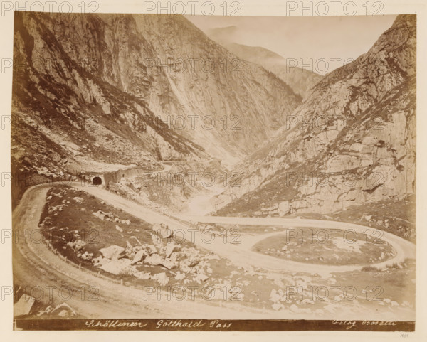 View of the Gotthard Pass, album page, photograph, This photo is part of an album., inscription: 'Schöllenen Gotthard Pass, Fotog Bosetti', annotation: '1898', photographer: Bosetti, Gotthard Pass, 1898, paper, albumen print, height 265 mm, width 350 mm, road, path, A sepia-toned landscape showing a winding dirt road curving through a rocky mountain pass with steep cliff faces on both sides, scattered boulders and rocky scree along the slopes, a tunnel entrance with a stone facade where the road enters one side of the valley, patches of low vegetation and grass among the rocks, distant hazy peaks partially obscured by mist, and a narrow riverbed or gorge running down the center of the scene.