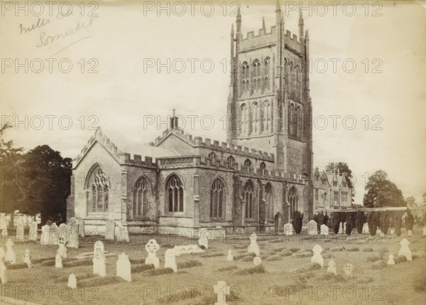 Mells Ch. Somerset, Exterior of the Church of St. Andrew with a churchyard in front in Mells, photograph, Part of an English family album with photos of people, travels, cricket and artworks., Mells, c. 1860 - c. 1870, photographer, Somerset, paper, albumen print, height 163 mm x width 218 mm, churchyard, cemetery, church (exterior), parts of church exterior and annexes: tower, gravestone, tombstone, A sepia-toned photograph of a stone church with Gothic-style windows and a prominent square tower topped with battlements and pinnacles, set behind a graveyard with rows of headstones and carved grave markers on grassy ground; the church has arched window tracery, crenellated rooflines, buttresses, and a small cross on a gable, while trees and additional stone buildings are visible in the background under a pale sky.