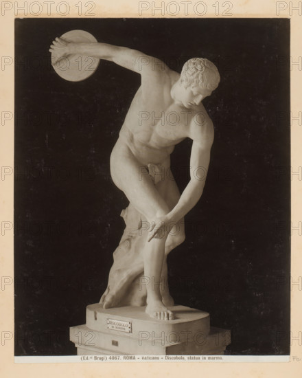 Roma - Vaticano - Discus Thrower, marble statue, Sculpture of a discus thrower in the Vatican Museums in Vatican City, photograph, Part of Photo album with photographs of sights and artworks in Italy., number: '4067', photographer: Edizioni Brogi, Vatican Museums, c. 1875 - in or before 1907, Vatican City, paper, gelatin silver print, height 250 mm x width 198 mm, sculpture, discus-throwing, A light-colored marble statue of a nude male athlete is shown against a dark background, captured in a dynamic throwing pose with one arm extended backward holding a circular disc and the other arm reaching down toward a bent leg, the head turned downward and to the side with stylized curly hair and a focused facial expression, the muscular torso and limbs sculpted with visible anatomical detail, one foot planted on a round base and the other leg slightly raised and supported by a tree-trunk-like element behind the figure, the base rests on a stepped plinth and the image has a narrow light-colored ...