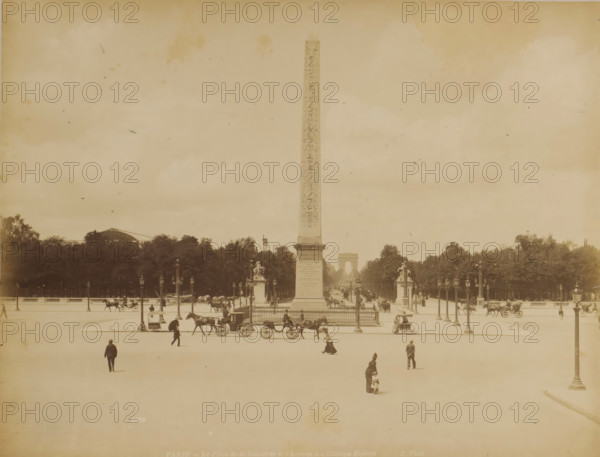 PARIS. - The Place de la Concorde and the Avenue of the Champs-Élysées, View of Place de la Concorde with the Luxor obelisk and the Avenue of the Champs-Élysées in the distance in Paris, photograph, Part of a travel album with photographs of sights in Sweden, Norway, Denmark, Bavaria, Milan, and Paris., number: '1098', photographer: X phot., Paris, c. 1870 - c. 1890, paper, albumen print, height 211 mm x width 275 mm, monument, statue, square, circus, obelisk, needle, Place de la Concorde, Champs-Elysées, A wide open square with a tall slender obelisk rising from a fenced base at its center, flanked by ornate lamp posts and sculpted pedestals, a distant arch visible along the central sightline beyond the obelisk, rows of trees forming a dark band behind the monument, horse-drawn carriages and horses moving along the roadway surrounding the obelisk, several pedestrians scattered across the open paved foreground including a woman with a small child and a few men walking, lamp posts linin...