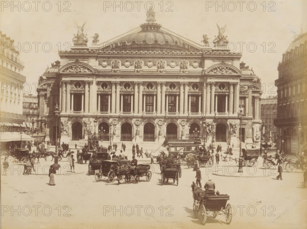 Carriages in front of the Palais Garnier in Paris, album page, photograph, This photo is part of an album., inscription: '604 Paris L'Opéra (Academie Nationale de Musique)', photographer: X phot., 1887 - 1910, X phot., photographer, paper, albumen print, height 208 mm x width 274 mm, historical persons, diligence, omnibus, horse-tram, animal traction, animal-drawn vehicle (carriage etc.), opera house, Paris, Palais Garnier, A wide frontal view of a large ornate stone building with a domed roof and sculptural figures on its roofline, a symmetrical facade with tall columns and arched openings at street level, decorative sculpted reliefs above the columns, and statues flanking the main entrances; in front of the building a busy street scene with many horse-drawn carriages and people walking or standing, some holding umbrellas, and a larger carriage approaching in the foreground with a driver seated at the front; surrounding the central building are multi-story urban buildings on either si...
