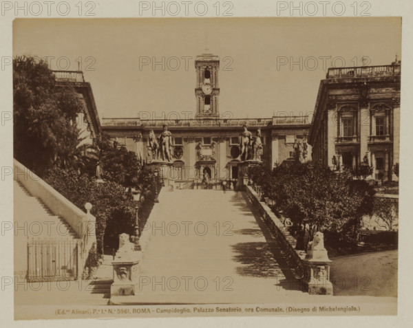 Stairs to the Senators Palace on the Capitoline Hill in Rome, Italy, Campidoglio. Palazzo Senatorio ora Comunale (Disegno di Michelangiolo), Roma, photograph, number: 'Po. Io. No. 5961.', photographer: Fratelli Alinari, Rome, 1852 - 1900, pasteboard, paper, albumen print, albumendruk, height 106 mm x width 139 mm, height 168 mm x width 223 mm, tower, clock tower, monumental adornment, staircase, Capitol, A wide stone staircase flanked by low balustrades leads upward between landscaped terraces with trimmed bushes and trees; sculpted lion figures sit atop square pedestals at the base of the approach and larger classical statues of human figures with horses and drapery stand on raised plinths nearer the top; a grand neoclassical building with ornate windows, decorative reliefs, and a central tower with a round clock face rises behind the statues, with a formal doorway and sculpted oval panels visible on the façade; a row of lamp posts lines the walkway and a pair of side buildings with t...