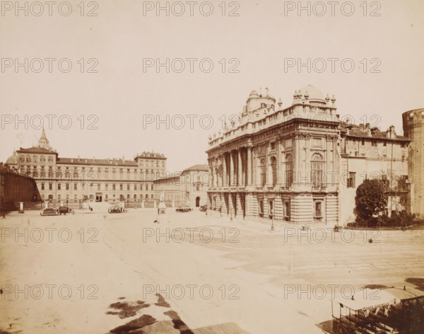 View of the Piazza Castello in Turin, Italy, Piazza Castella, Torino, photograph, address: 'VIA GERRAIA CORSO SICCARDI, TORINO', photographer: Fotografia Subalpina, Turin, 1899 - 1910, Piedmont, pasteboard, paper, albumen print, height 260 mm x width 316 mm, square, circus, exterior, representation of a building, Piazza Castello (Turin), A wide open paved square bordered by large classical buildings with ornate facades, tall arched windows, columns, balustrades, and sculptural details, one prominent building with domes and ornamental statues along its roofline at the right, an extended multi-story building stretching across the background to the left with a decorative roof element, scattered small horse-drawn carriages and benches positioned across the square, a lone tree and shrubbery near the right edge beside a simpler building, a cylindrical tower partially visible at the far right, and an overall pale, sepia-toned appearance.