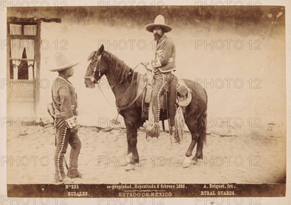 Rurales, Rural Guards, Two Mexican men in traditional clothing, one of them on horseback, Estado de Mexico, photograph, copyright notice: 'es-propriedad, depositada 6 febrero 1896.', number: 'N. 235', photographer: Abel Briquet, Mexico, 1896, North America, pasteboard, paper, albumen print, height 133 mm x width 194 mm, height 160 mm x width 210 mm, adult man, horse, A sepia photograph shows two men and a horse on a cobblestone surface in front of a pale wall with a window partially draped with curtains; one man stands facing the horse wearing a wide-brimmed hat and a decorated jacket and trousers, the other sits astride the horse wearing a similar wide-brimmed hat, a jacket with decorative trim, and a beard, holding the reins; the horse is saddled with ropes, blankets, and gear hanging from the saddle, and both men's clothing and the horse's tack feature rows of round metallic elements.