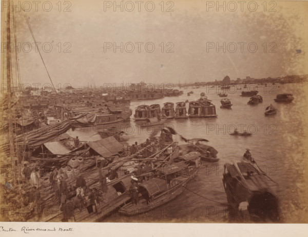 View of the river with boats near Guangzhou, photograph, annotation: 'Canton, Riverscene and boats', 1850 - 1900, photographer, paper, pasteboard, albumen print, height 230 mm x width 310 mm, harbour, river (landscape with figures, staffage), Canton (city), A wide river scene with many small wooden boats clustered near the bank and scattered across the water, several boats with curved canopies and others open, some boats docked alongside a crowded riverside area filled with tarps, woven baskets, ropes, and stacked cargo, numerous people standing or moving among the boats and along the dock, long masts and rigging visible on the left, a distant shoreline with low buildings and a single sail visible further out on the water, and a hazy sky above.