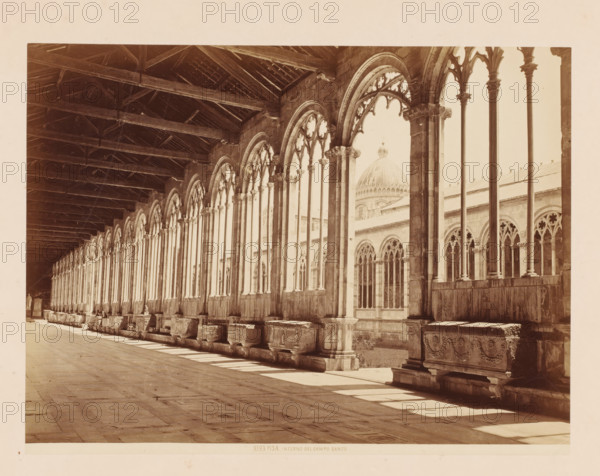 Interno del Campo Santo, Gallery in the Camposanto in Pisa, Italy, Pisa, photograph, number: '3393', address: 'GIACOMO BROGI, FOTOGRAFO-EDITORE, FIRENZE, LUNG ARNO DELLE GRAZIE 15', photographer: Giacomo Brogi (possibly), publisher: Edizioni Brogi, Florence, 1864 - 1881, Tuscany, pasteboard, paper, albumen print, height 344 mm x width 470 mm, gallery (spacious corridor), Piazza dei Miracoli, Camposanto (Piazza dei Miracoli), A long covered stone gallery with a wooden-beamed ceiling runs along the left side of the image, opening on the right to a series of pointed gothic arches supported by slender columns and decorated tracery, each arch revealing views of an exterior courtyard and architectural details beyond; stone sarcophagi with carved reliefs line the base beneath the arches, sitting on raised plinths and casting shadows on the tiled floor, while light streams through the openings creating alternating bands of sun and shade across the walkway.