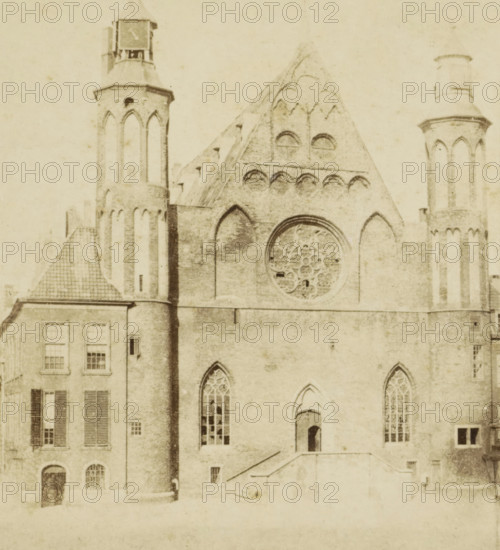 Ridderzaal on the Binnenhof in The Hague, Loterij Zaal Binnenhof, stereograph, inscription: 'fo-50', The Hague, 1852 - 1863, photographer, pasteboard, paper, albumen print, albumendruk, height 75 mm x width 150 mm, façade (or house or building), Binnenhof, Ridderzaal, A sepia-toned image of a large stone building with Gothic architectural features, showing tall narrow arched windows with tracery, a large circular rose window with ornate stonework set into a triangular gable, and flanking cylindrical towers with narrow vertical openings and conical tops; a lower attached section with rectangular windows and shutters abuts the main structure, and a staircase leads up to a small arched doorway set into the facade.