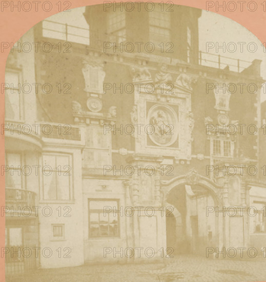 Passage of the Groothoofdspoort in Dordrecht, Dordrecht. La porte du port, stereograph, inscription: '11', number: '20 bis.', photographer: attributed to Jules Hippolyte Quéval, Dordrecht, 1873 - 1890, Attributed to, pasteboard, paper, albumen print, albumendruk, height 87 mm x width 177 mm, city-gate, Groothoofdspoort, A faded sepia photograph showing a section of an ornate building façade with sculpted decorative elements and reliefs, including a circular medallion with a carved figure, flanking ornamental urns, and detailed pilasters; rectangular windows with panes and a small balcony with a curved railing are visible on the left side; a large arched doorway with a patterned surround appears on the right, and a cobblestone street runs along the bottom of the image; the top of the image is rounded and framed by a colored border.