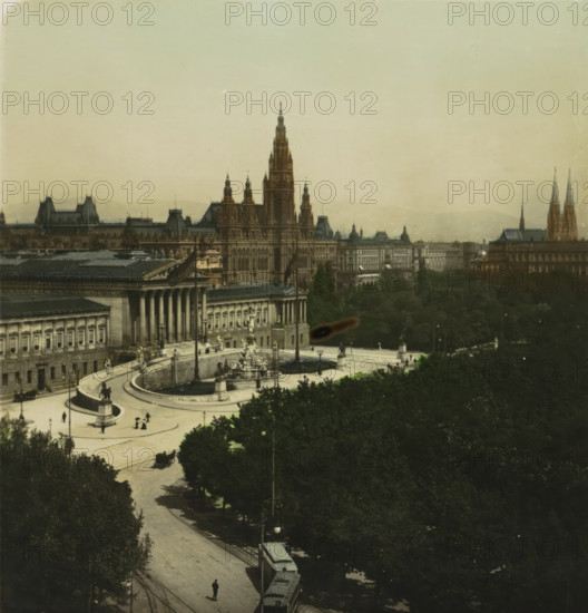 Burgring with the Austrian Parliament and Viennese Town Hall in the background, Vienna, Wien. Burgring mit Parlament, stereograph, inscription: 'Oesterreich. Vienna. Burgring mit Parlament., Austria. Vienna 'Burgring' with Parliament., Autriche. Vienne. 'Burgring' et Parliament., Austria. Viena. 'Burgring' y Parlamento.', monogram: 'BW', number: '17.', photographer: BW, 1898 - 1935, Lower Austria, paper, baryta paper, gelatin silver print, hand coloring, developing gelatin silver print, height 88 mm x width 169 mm, city-view in general, 'veduta', A wide aerial view of a cityscape featuring a large ornate building with tall pointed towers and intricate facades centered in the midground, flanked by other classical buildings with columns and decorative roofs, a curved plaza with fountains and statues in front of the buildings, tree-lined streets and dense dark foliage occupying the lower half of the image, small figures and horse-drawn carriages on the plaza and streets, a tram on tracks ...