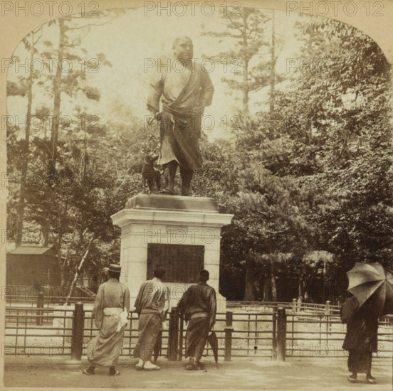 Statue of Takamori Saigo in Uenopark, Tokyo, The Image of Saigo, Japan, stereograph, number: '1580.', number: '63', number: '30', Uenopark, publisher: Griffith & Griffith, Philadelphia (possibly), 1898 - 1912, photographer, North America, Kanto, pasteboard, paper, albumen print, albumendruk, height 89 mm x width 178 mm, monument, statue, A sepia photograph of a stone statue on a pedestal showing a robed figure standing with one hand on the hip and the other holding a leash attached to a dog at the figure's side, set among tall trees and dense foliage; in front of the pedestal three people in traditional clothing stand facing the statue with their backs to the camera, and to the right a person stands holding an open umbrella, while a fenced railing runs across the foreground.