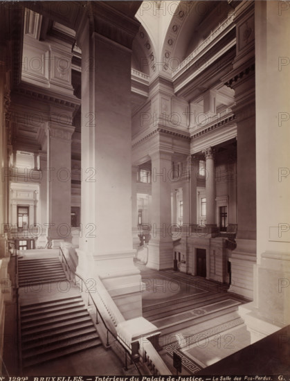 Interior of the Salle des Pas-Perdus in the Palace of Justice in Brussels, Belgium, Intérieur du Palais de Justice - La Salle des Pas-Perdus, Bruxelles, photograph, number: 'No 1299B', photographer: Gustave Hermans, Brussels, 1884 - 1914, paper, albumen print, height 281 mm x width 218 mm, court building, interior, representation of a building, Palace of Justice (Brussels), A large interior space with high vaulted ceilings, massive square columns with molded capitals, decorative cornices and entablatures, broad staircases with balustrades leading between floors, patterned stone flooring with geometric borders and a central circular design, tall fluted columns with ornate capitals, multiple doorways and windows set into paneled walls, railings along upper galleries, layered archways and recessed panels, and soft light casting shadows across the architectural surfaces.