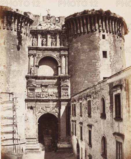 Gate of Castel Nuovo in Naples, Italy, Arc triomphe Aragymes au Chateau Menso (1370), Naples, photograph, number: 'No. 4038', number: '26.', number: '12', photographer: attributed to Giorgio Sommer, 1857 - 1914, Attributed to, pasteboard, paper, albumen print, albumendruk, height 405 mm x width 307 mm, castle, gate, entrance, Castel Nuovo, A sepia-toned photograph of a large stone gateway flanked by two massive rounded towers with battlements and narrow windows, the gateway richly carved with sculpted figures in niches, relief panels, ornate columns, and decorative arches, the central archway opening into a dark passage above which sits a large semicircular recessed niche and rows of sculpted statues, vines and vegetation growing on parts of the stonework, scaffolding visible along one side of the structure, and a weathered multi-windowed building with shuttered and arched openings lining a narrow street beside the gateway.